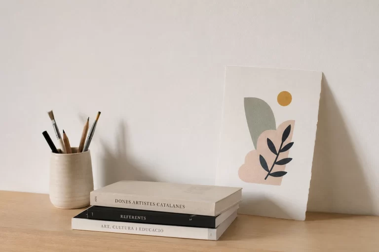 Materials artístics i llibres sobre dones artistes catalanes en un espai de treball minimalista.